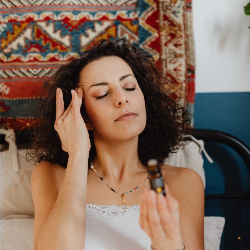 Mujer aplicándose aceite esencial en el rostro