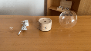 Difusor Bulle de Pranarôm desmontado sobre la mesa, mostrando la base de madera, cúpula de cristal, depósito y accesorios antes del montaje.