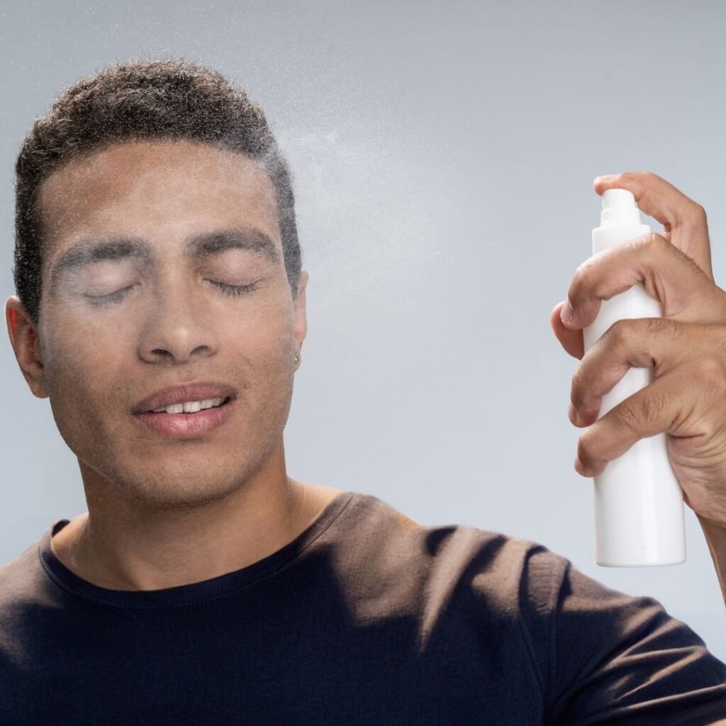 Hombre aplicando hidrolato facial en el rostro para refrescar e hidratar la piel.